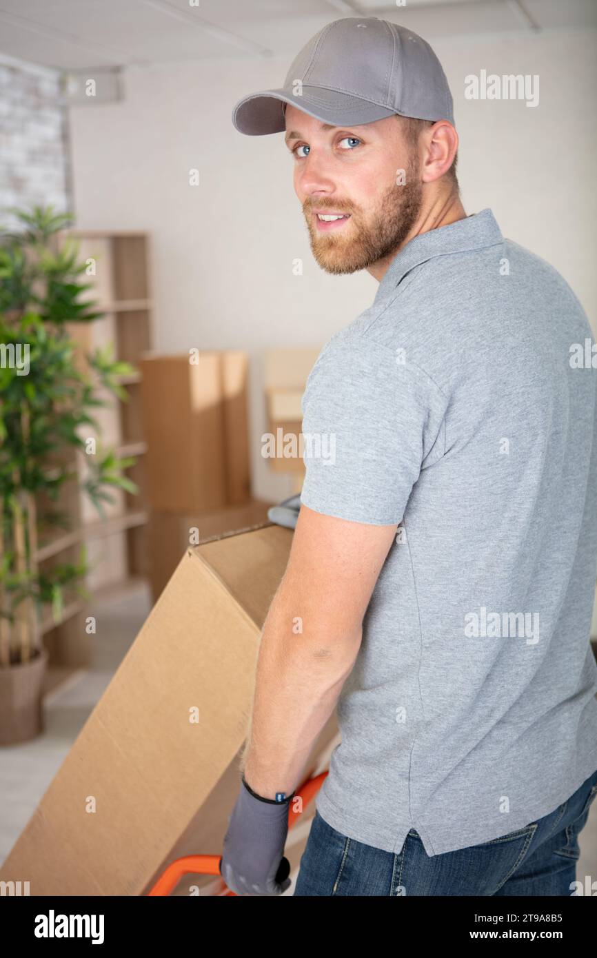delivery man pushing a stack of boxes on a trolley Stock Photo - Alamy