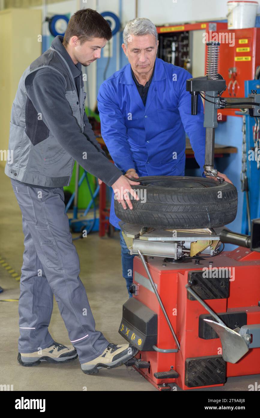 apprentice mechanic and teacher retreading wheel in automotive