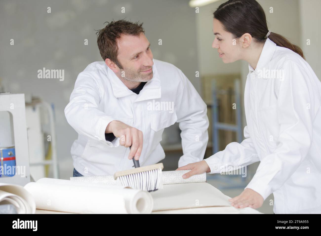 decorating team applying paste to wallpaper Stock Photo