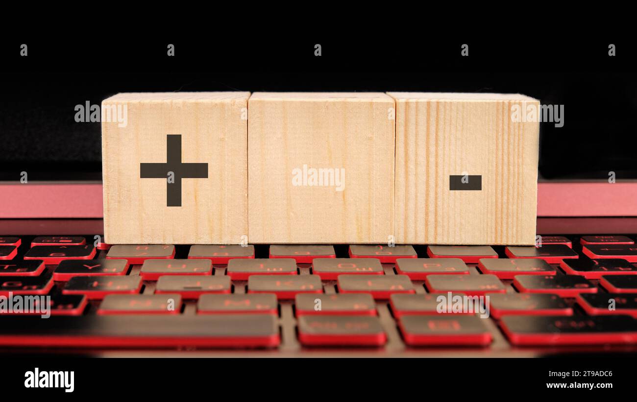 business concept.. Plus, minus symbols the inscription on wooden cubes on the laptop keyboard. Stock Photo