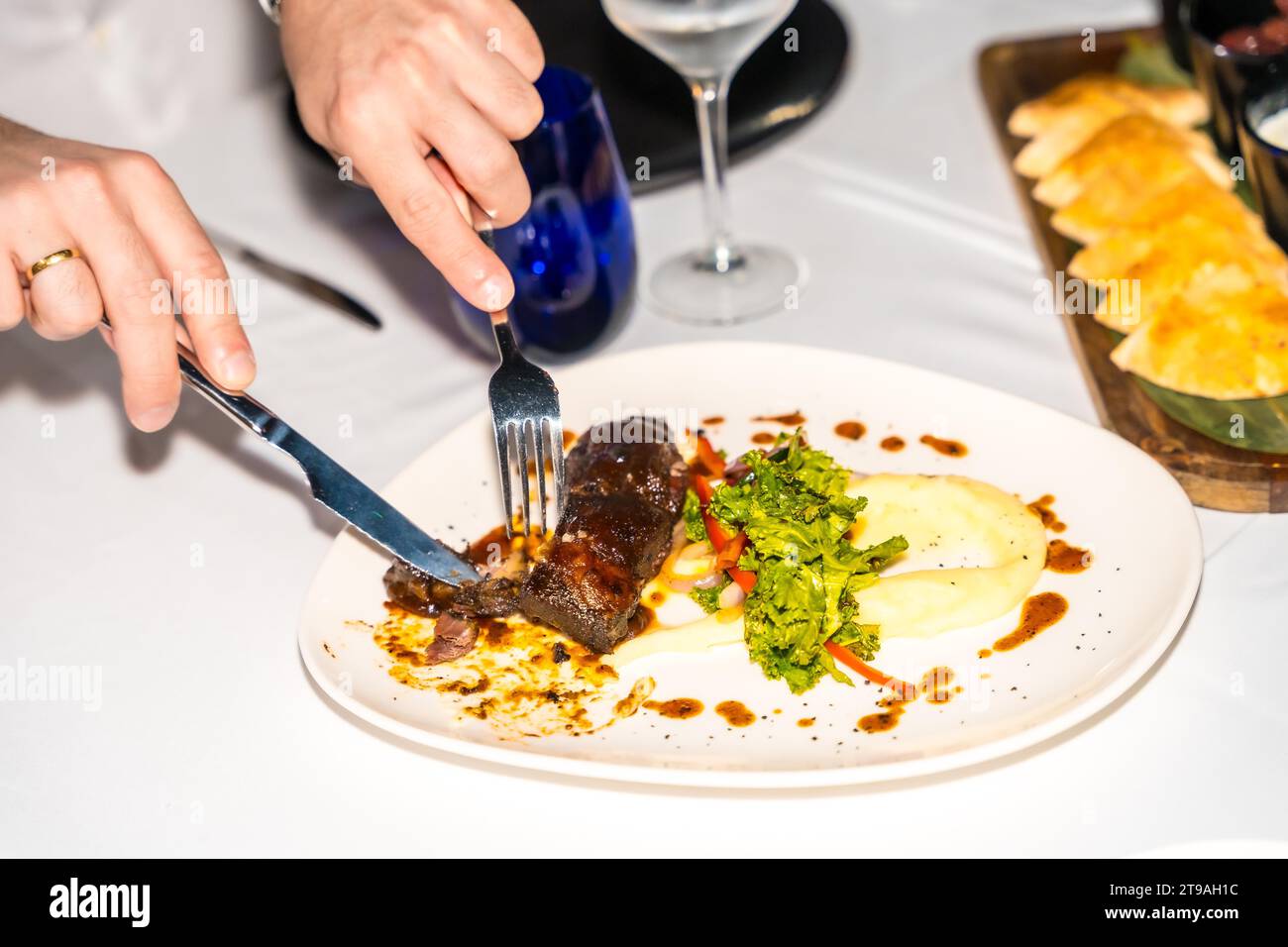 Top view of a man cutting meat in a luxury restaurant Stock Photo