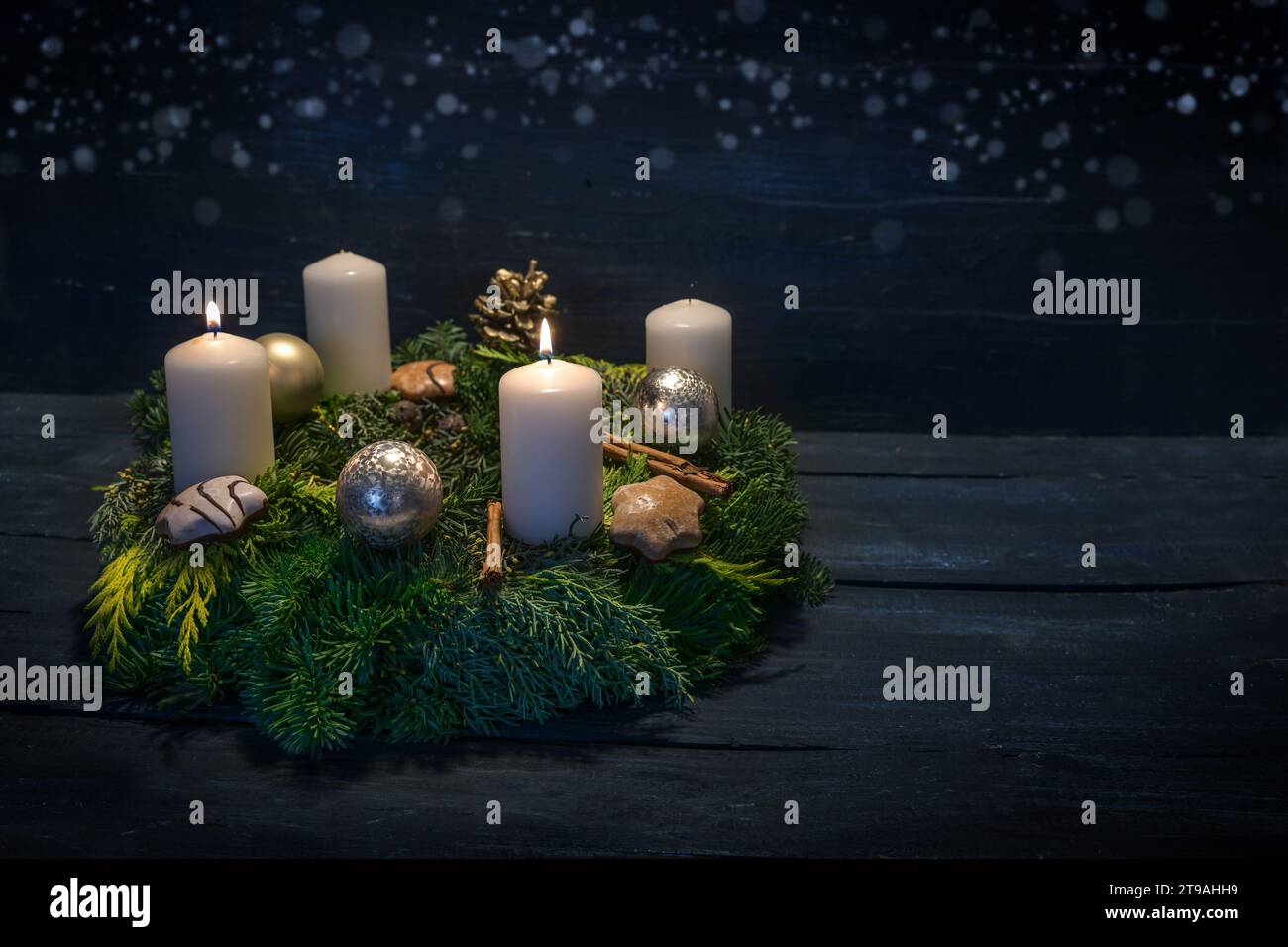 Green advent wreath with white candles, two are lit for second advent, Christmas decoration and cookies, dark blue wooden background with star bokeh, Stock Photo