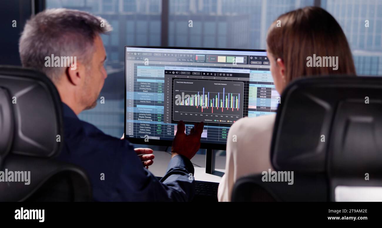 Working Analyst at Desktop Computer with Spreadsheets Stock Photo