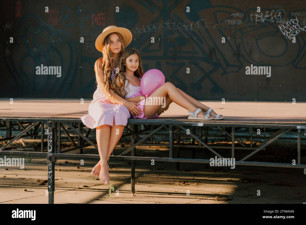 Portrait of mother and daughter in pink dresses with flowing long hair ...