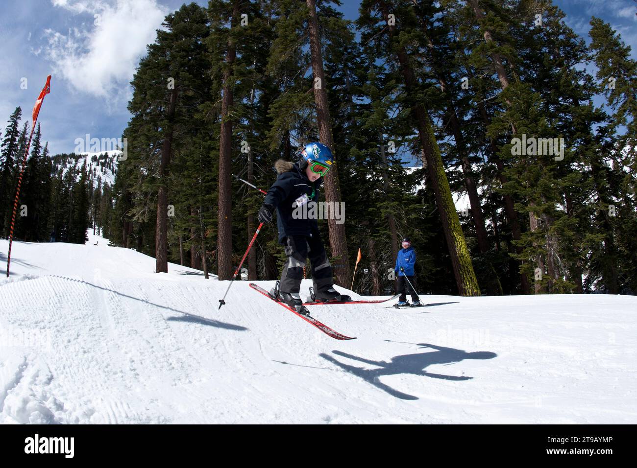 Young skier jumping in a terrain park while his instructor looks on. Stock Photo
