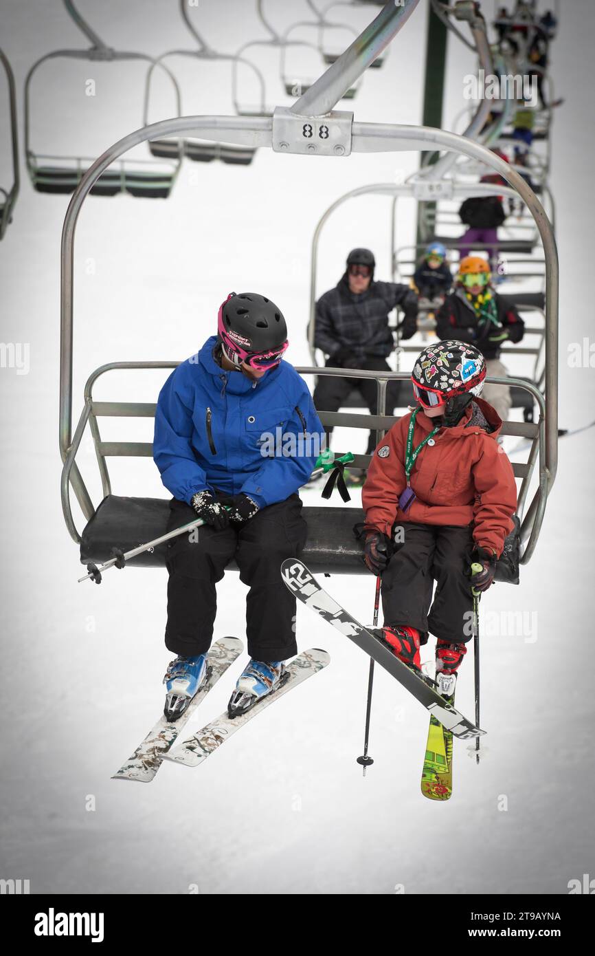 Ski instructor laughing with a young skier on a chairlift. Stock Photo