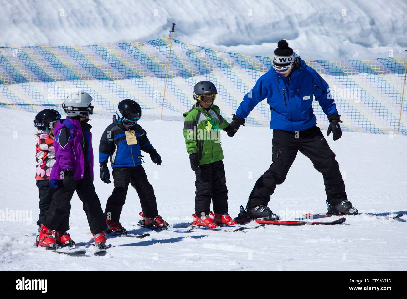 Ski Instructor helping three young skiers on a bunny slope. Stock Photo