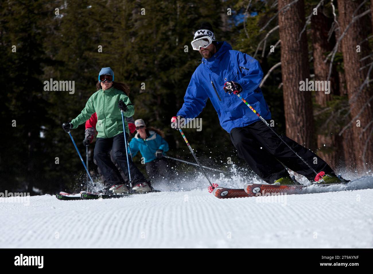 Low angle perspective of a ski instructor skiing with his class behind him. Stock Photo