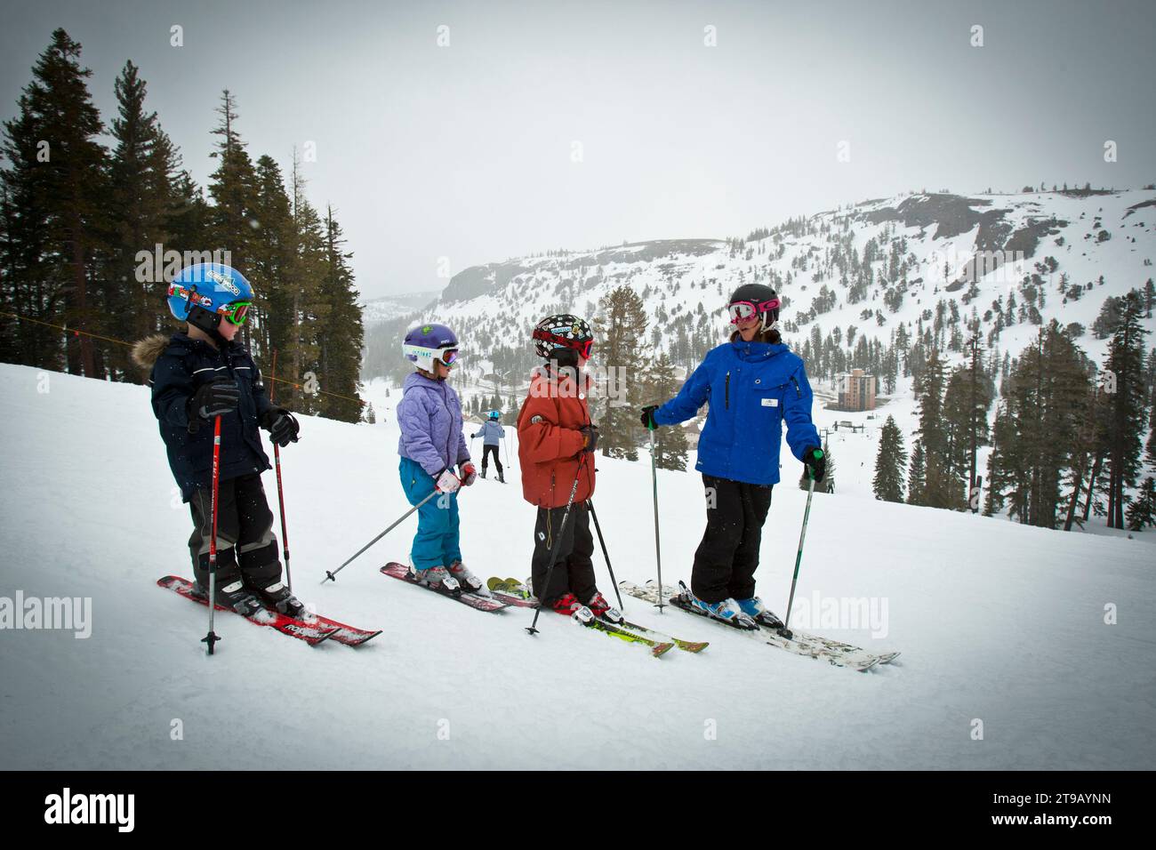 Ski instructor with three young students on a slope at a ski resort. Stock Photo
