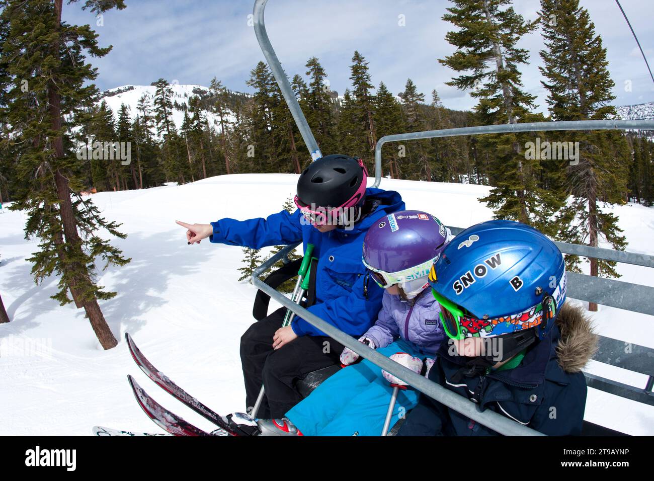 Ski instructor with two young skiers on a chairlift. Stock Photo