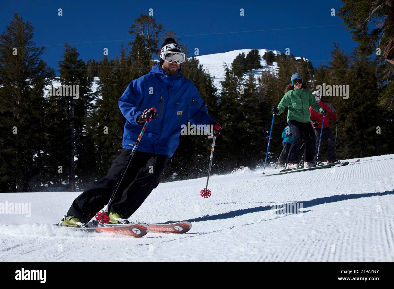 Low angle perspective of a ski instructor skiing with his class behind him. Stock Photo