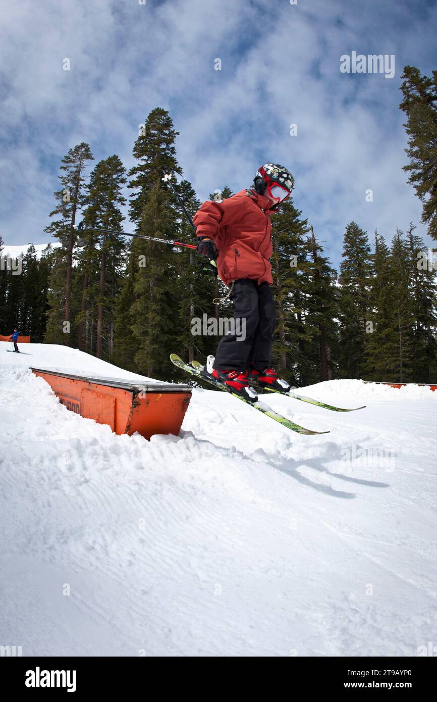 Young skier jumping off of a box in a terrain park. Stock Photo