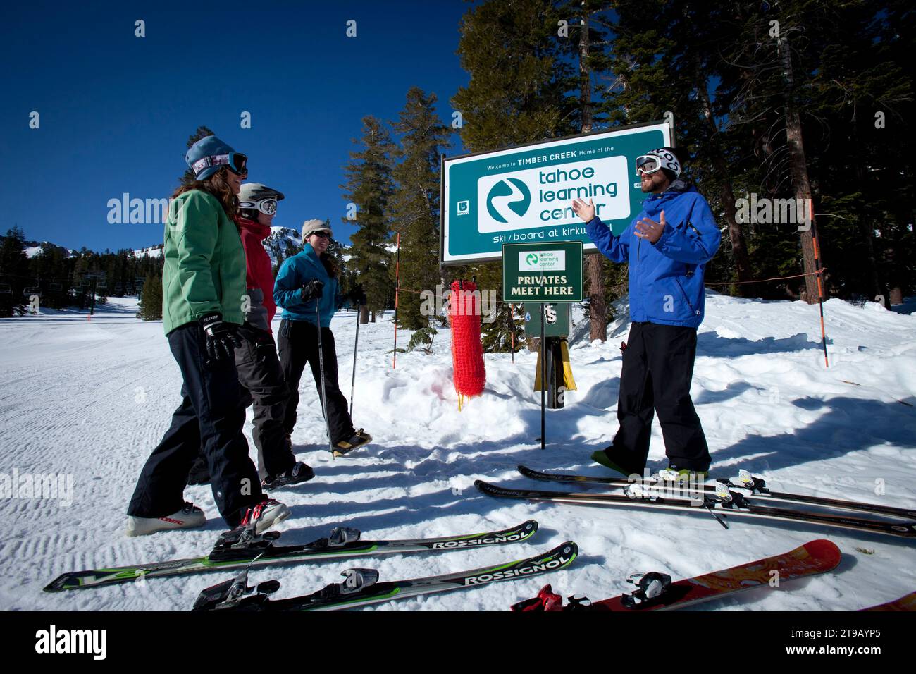 Three students and one ski instructor at the base of a slope. Stock Photo