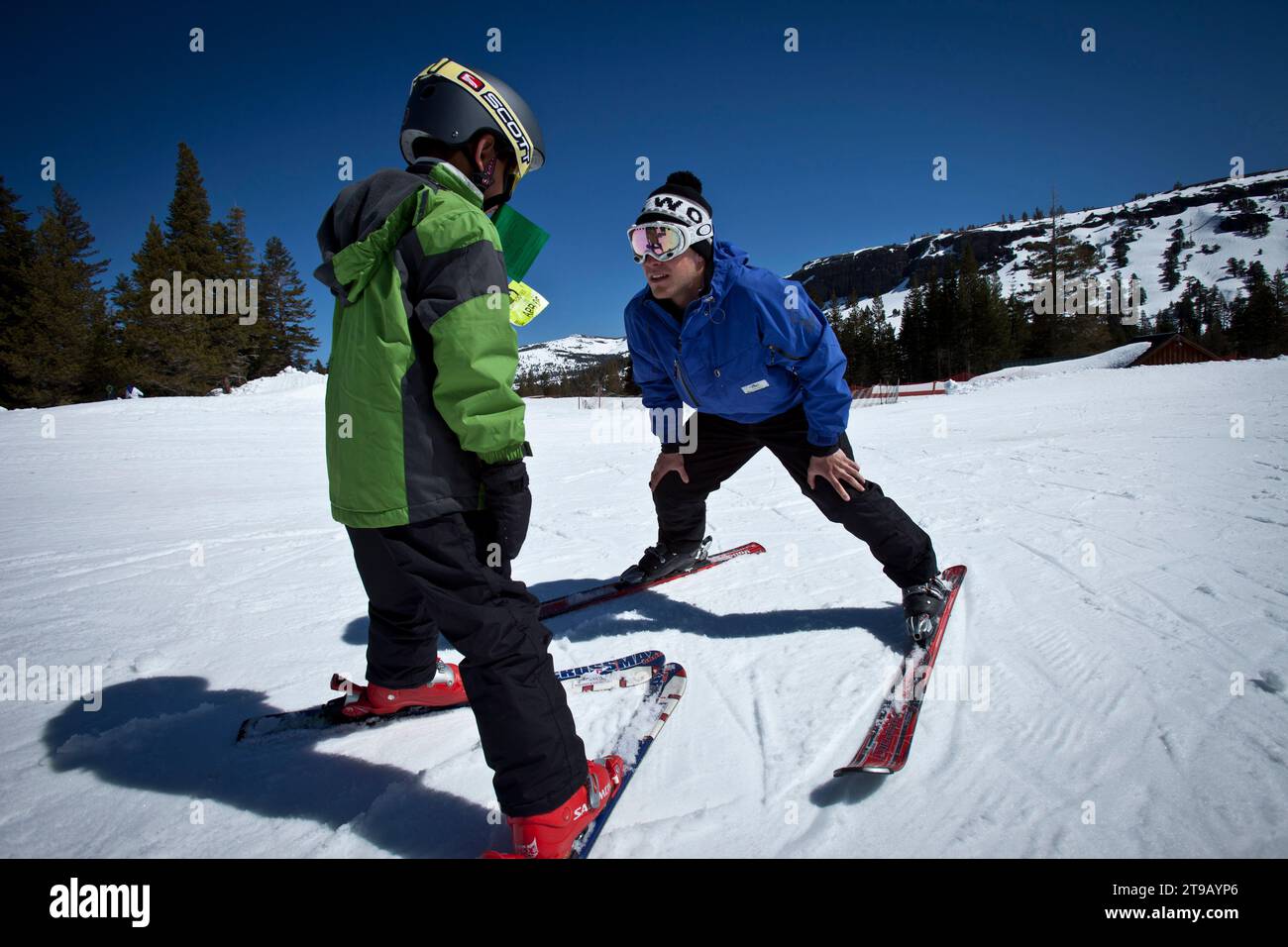 Ski Instructor helping a young skier on a bunny slope. Stock Photo
