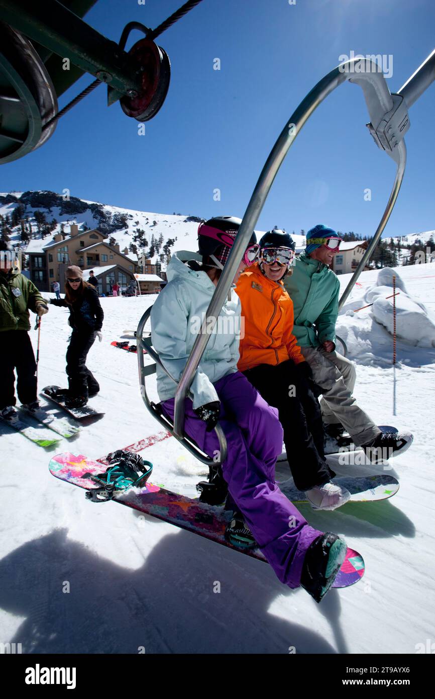 Snowboard instructor and two students getting on a chairlift. Stock Photo