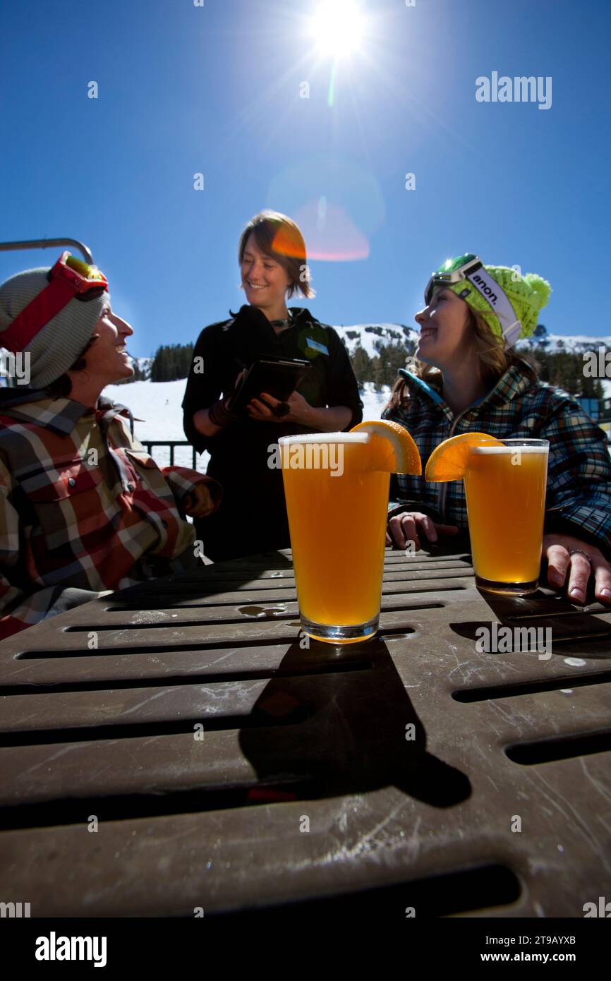 Young couple ordering food and beer on an outdoor patio at a ski resort. Stock Photo