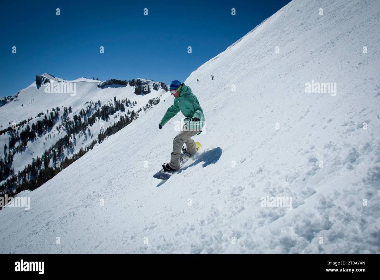Snowboarder riding spring conditions with a nice view. Stock Photo