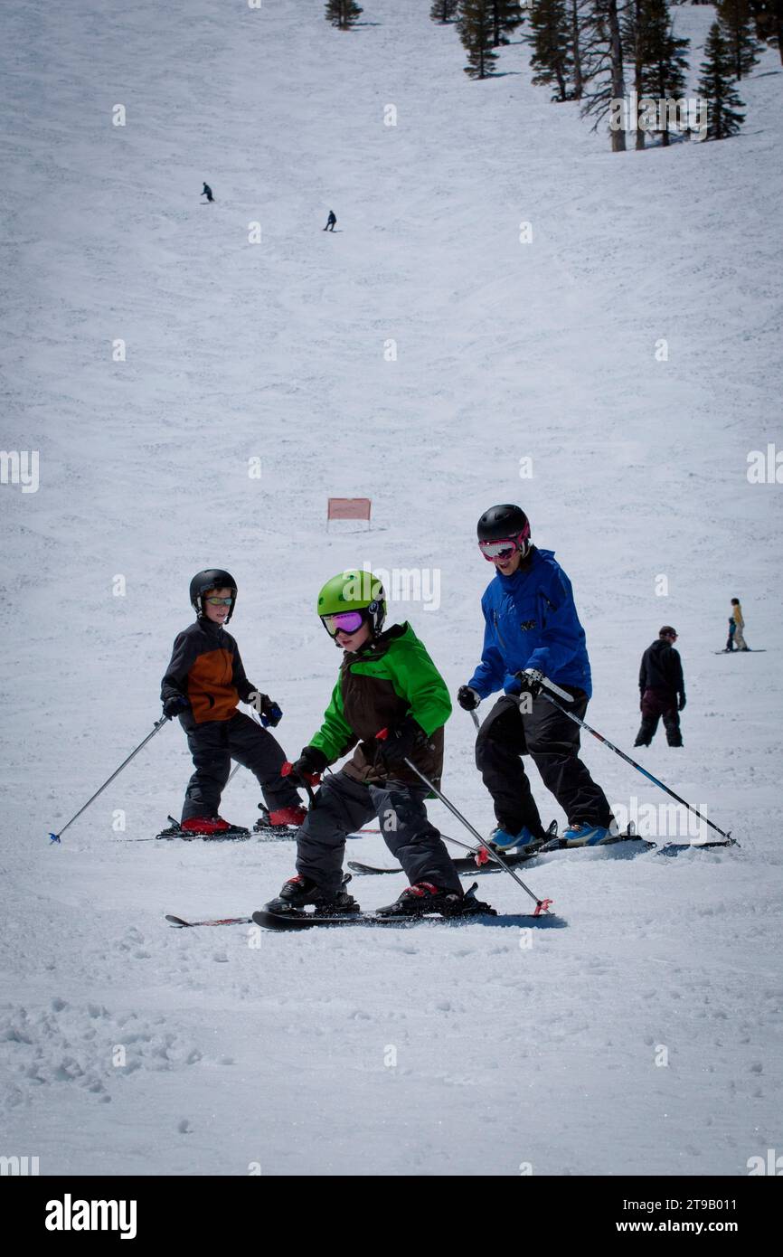Two young skiers with their ski instructor making turns down the mountain. Stock Photo