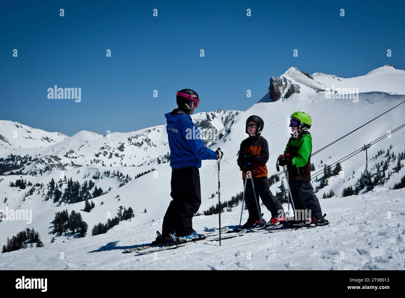Two young skiers with their ski instructor looking over a big view. Stock Photo