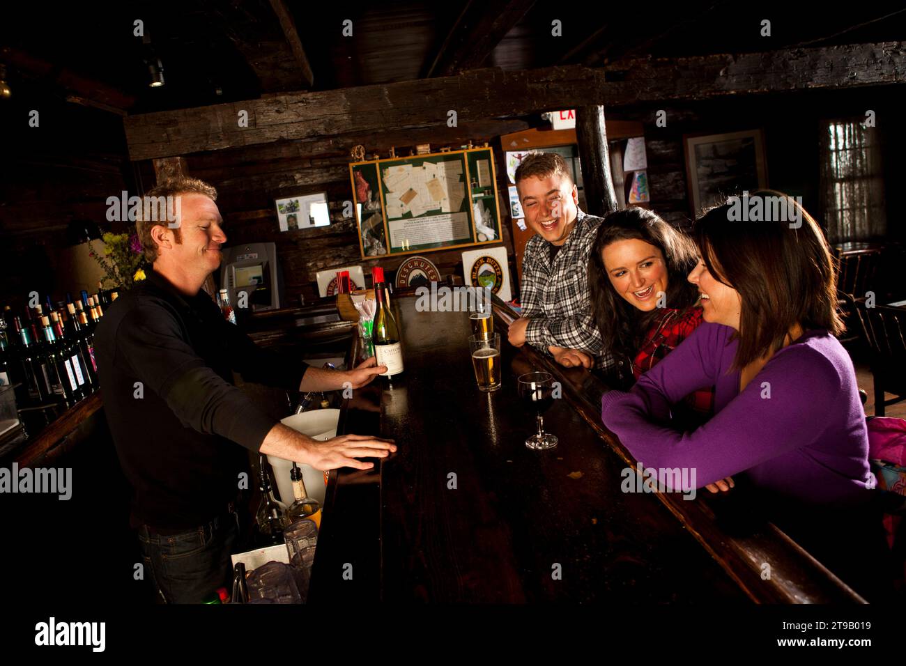 Two men and two women having beer and wine in an old lodge. Stock Photo