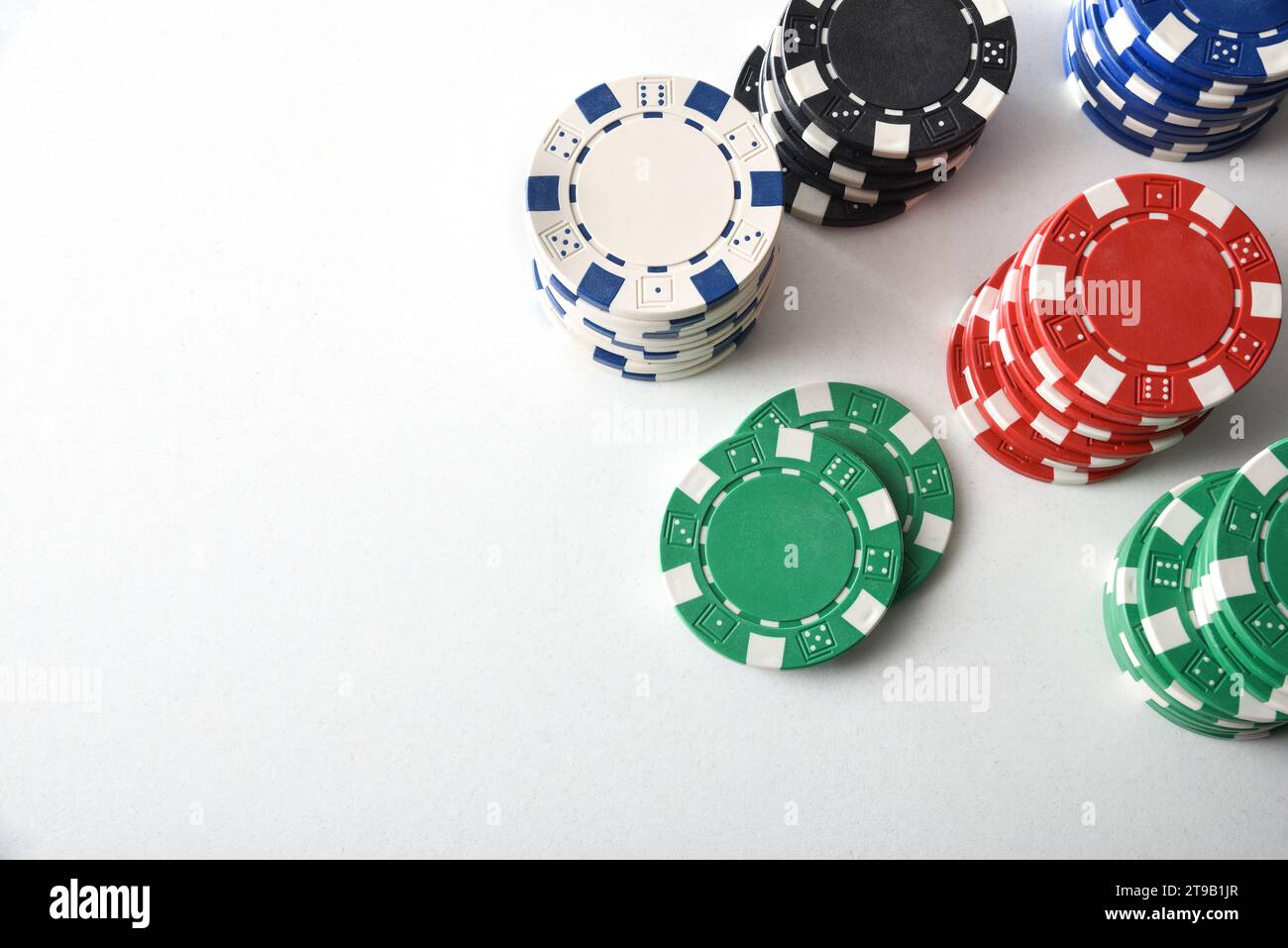 Various stacks of casino game bet chips of various colors on white table. Top view. Stock Photo