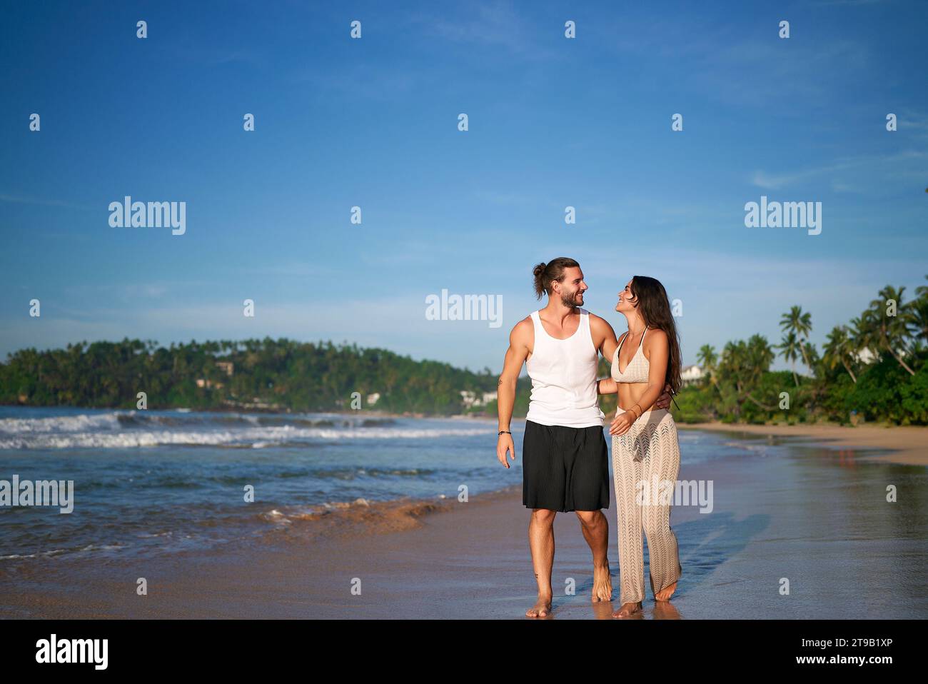 Romantic couple strolls on tropical beach at sunset. Man and woman in ...