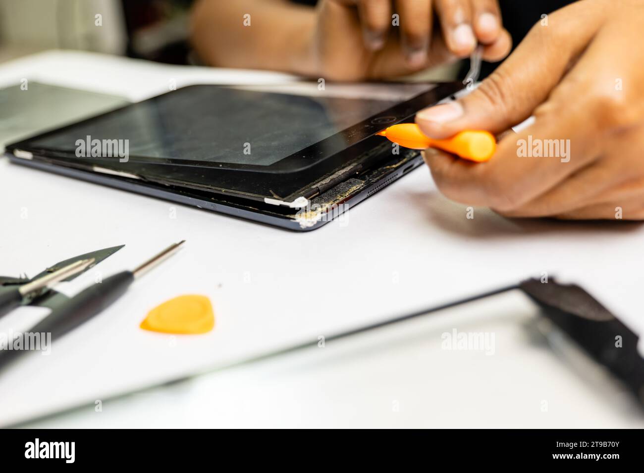 A skilled technician meticulously removes a tab's display using specialized tools Stock Photo