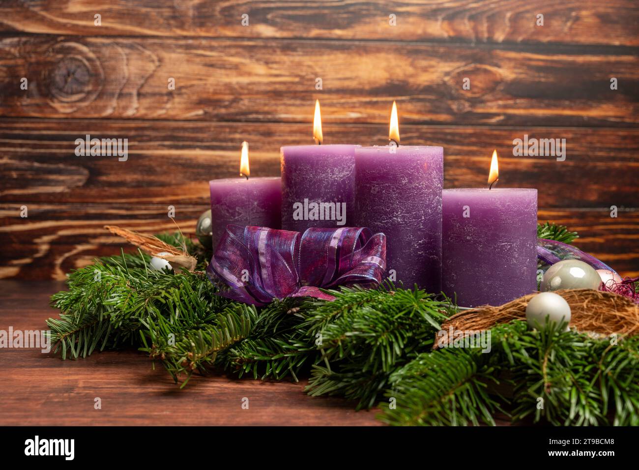Augsburg, Bavaria, Germany - November 24, 2023: Christmas wreath with four burning purple candles for Advent *** Weihnachtskranz mit vier brennenden lila Kerzen zur Adventszeit Stock Photo