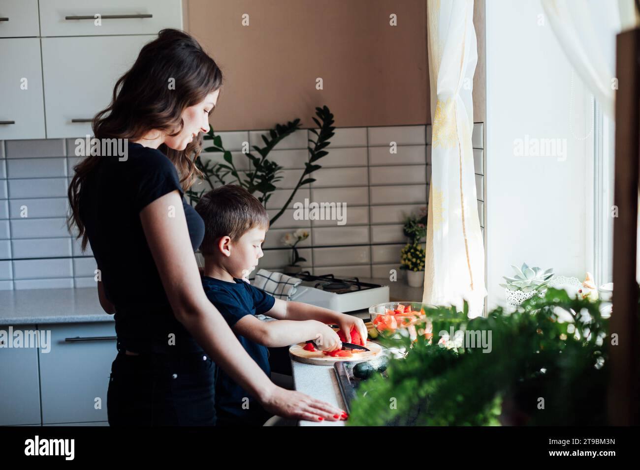housewife with son cooking food dinner in kitchen Stock Photo