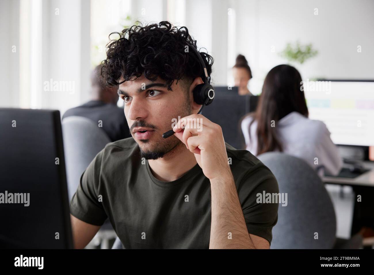 Man wearing headset using desktop PC in office Stock Photo