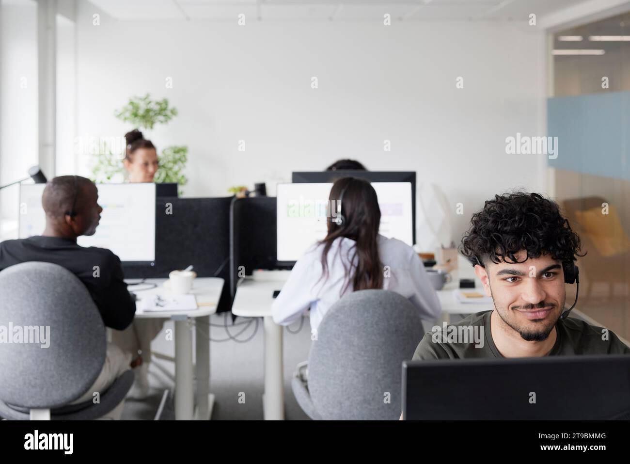 Man wearing headset using desktop PC in office Stock Photo