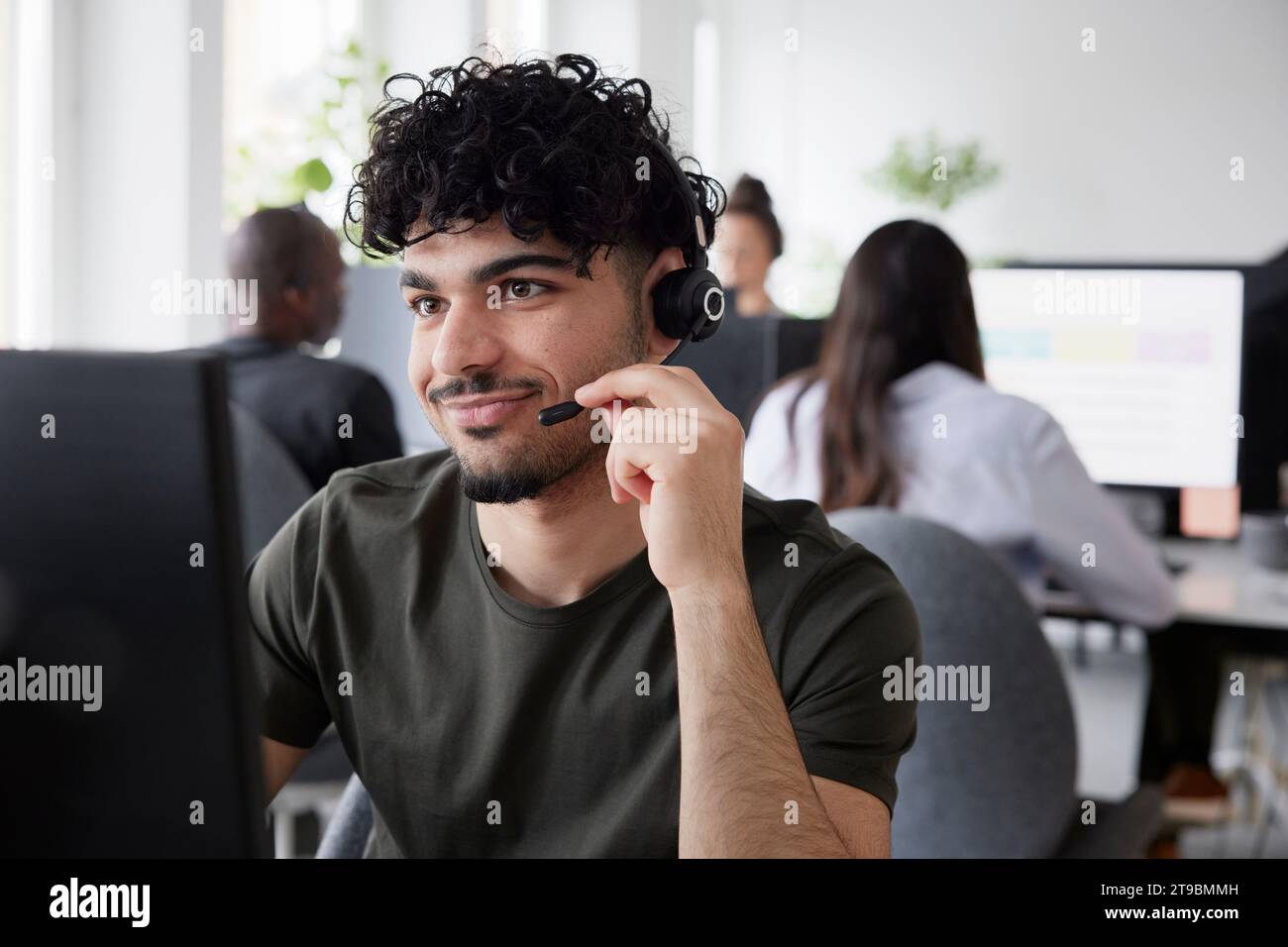 Man wearing headset using desktop PC in office Stock Photo