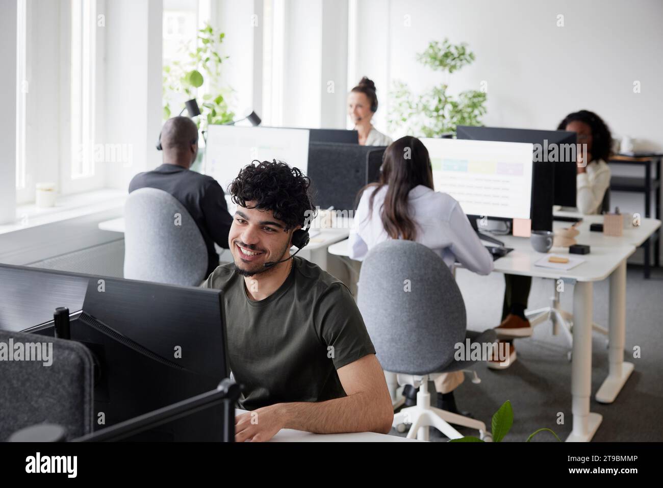 Man wearing headset using desktop PC in office Stock Photo