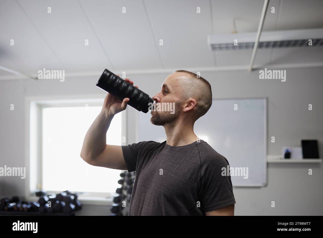 Side view of man drinking water in gym Stock Photo - Alamy