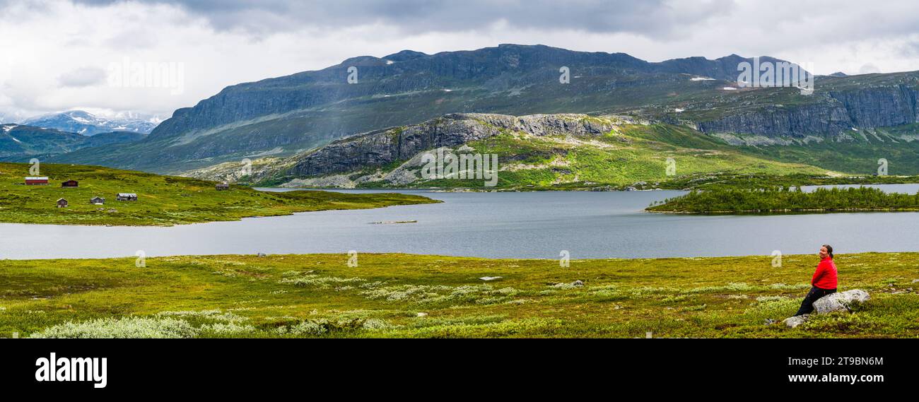 Female hiker sitting in mountain landscape near lake Stock Photo