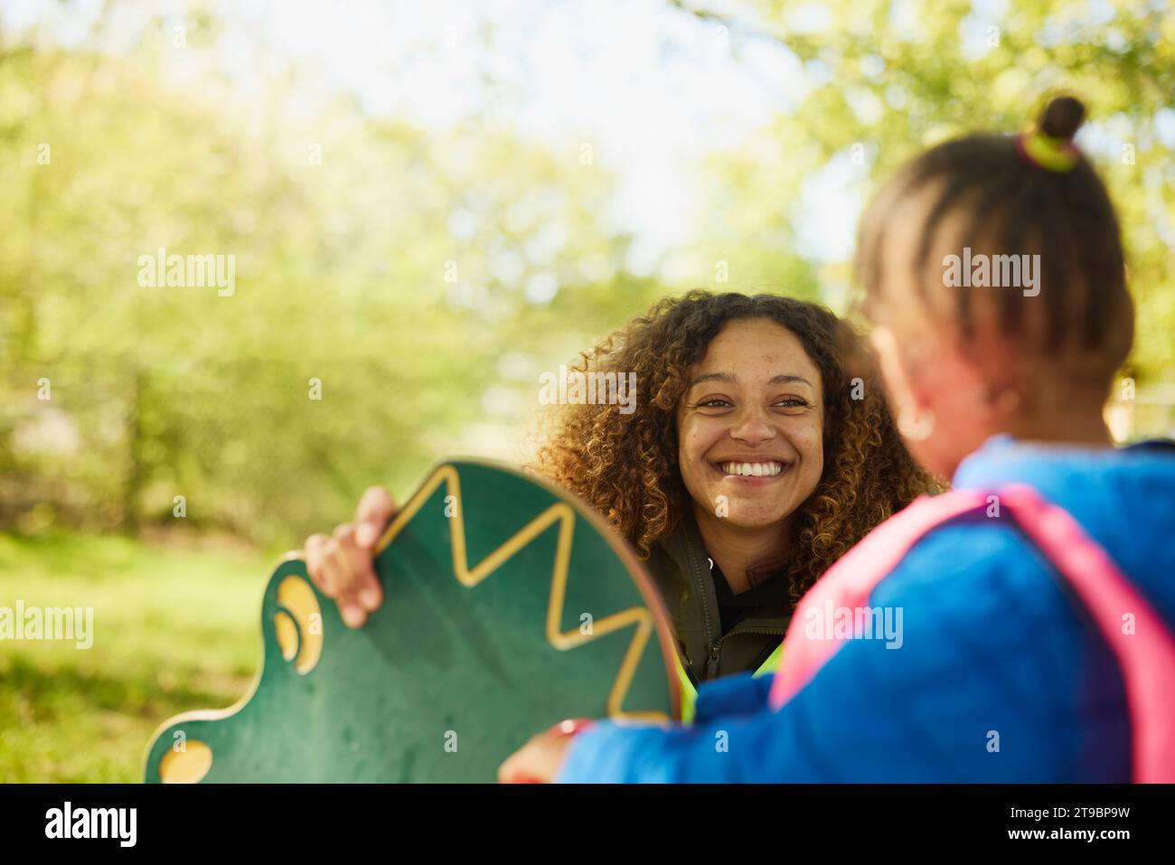 Smiling female teacher taking care of girl at playground Stock Photo