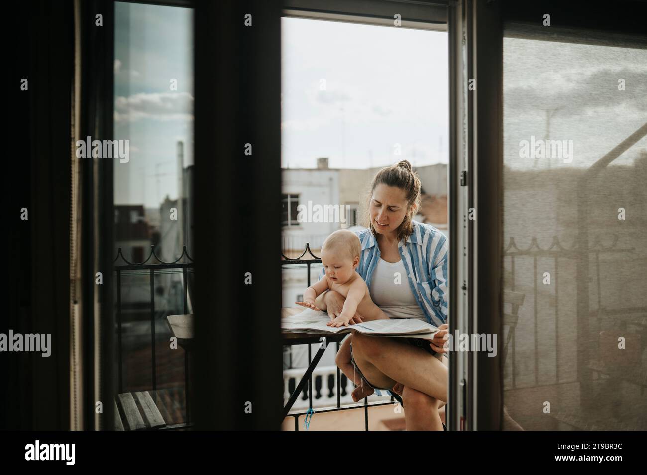 Mother relaxing with baby on balcony in summer Stock Photo