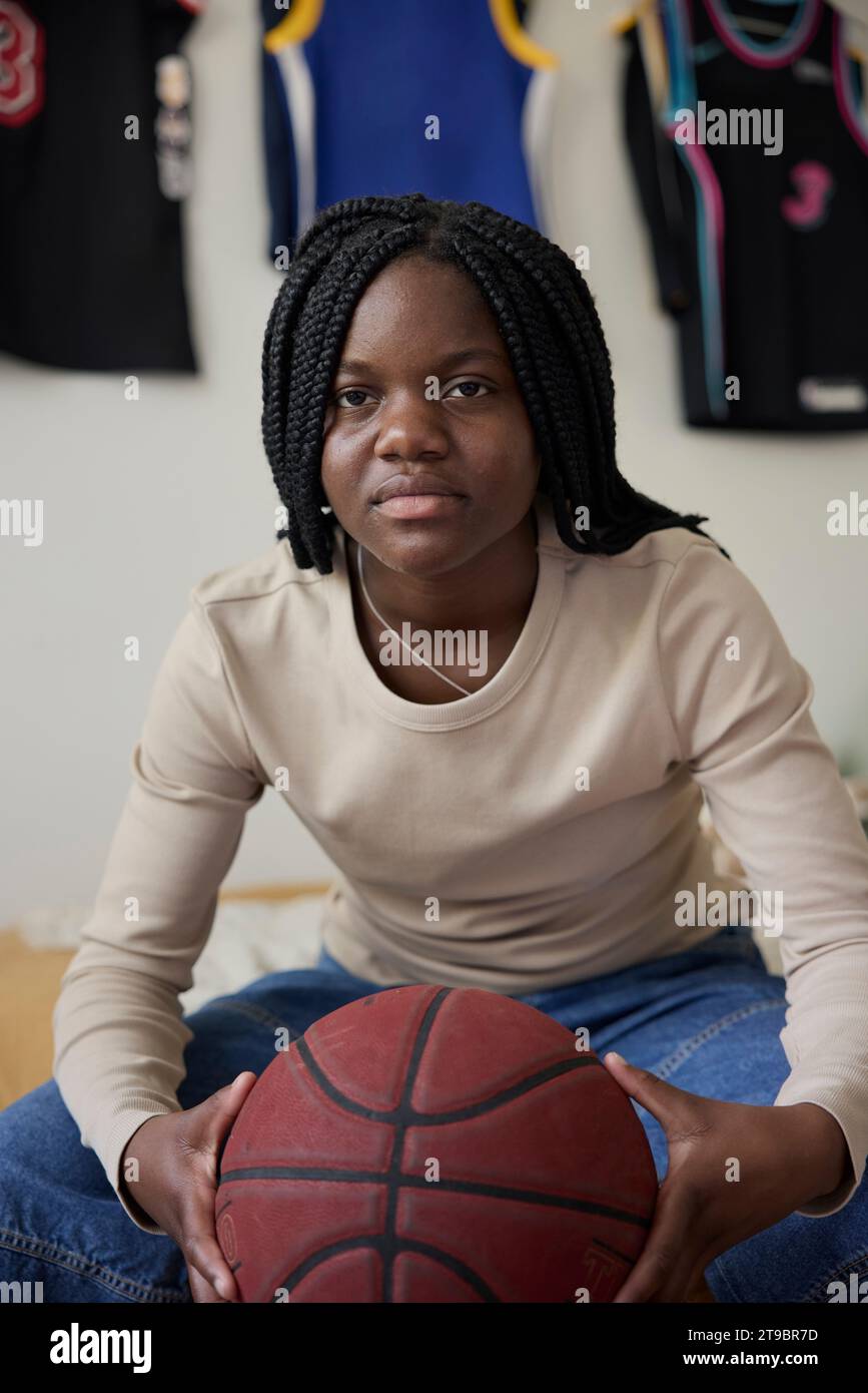 Portrait of teenage girl holding basketball while sitting at home Stock Photo