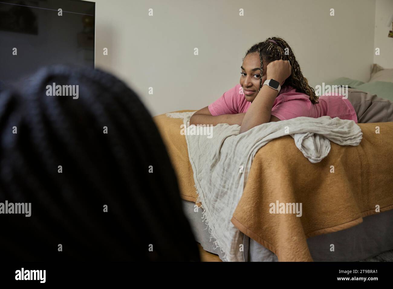 Teenage girl with head in hand lying on bed and looking at her friend Stock Photo