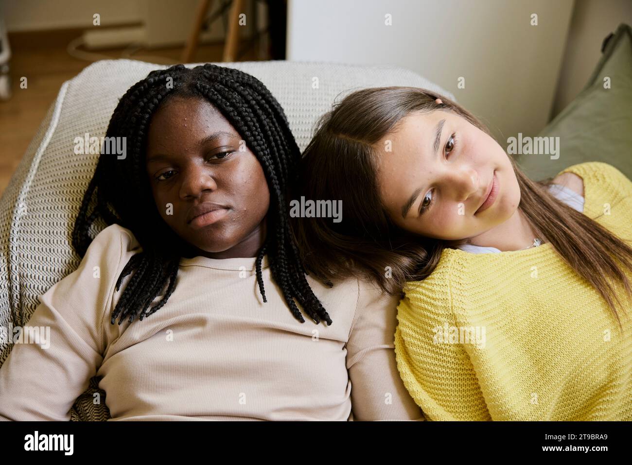 Multiracial female teenager friends lying down while resting at home Stock Photo