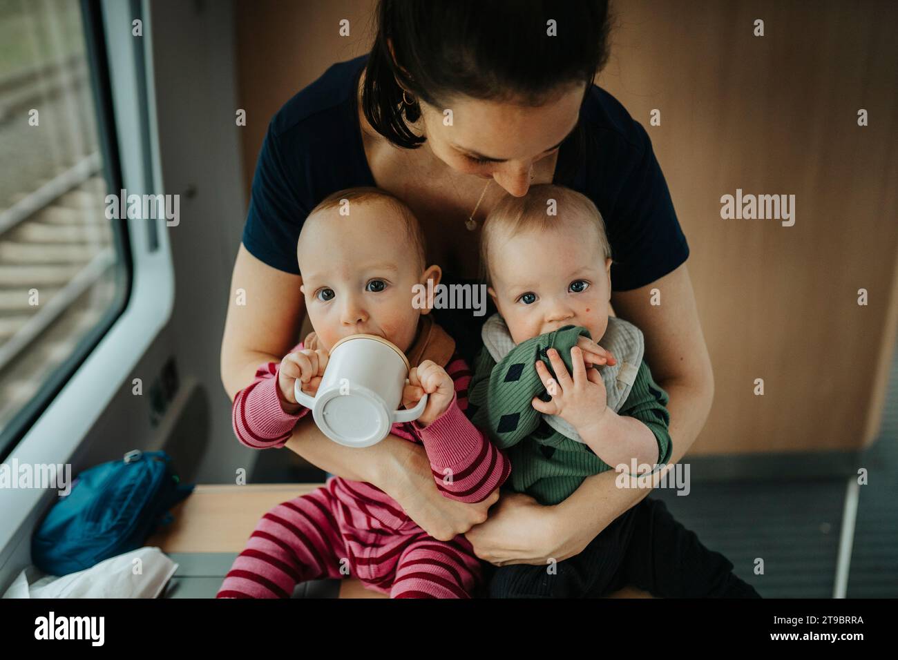 Mother embracing twin babies at home Stock Photo