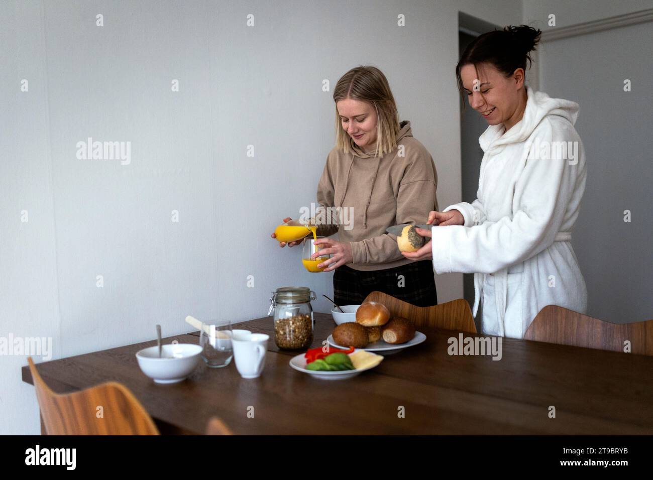 Smiling lesbian couple preparing breakfast at dining table Stock Photo