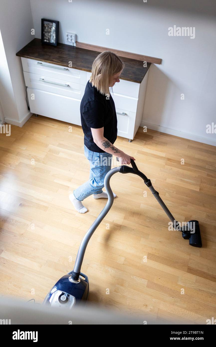 High angle view of young woman using vacuum cleaner on hardwood floor at home Stock Photo