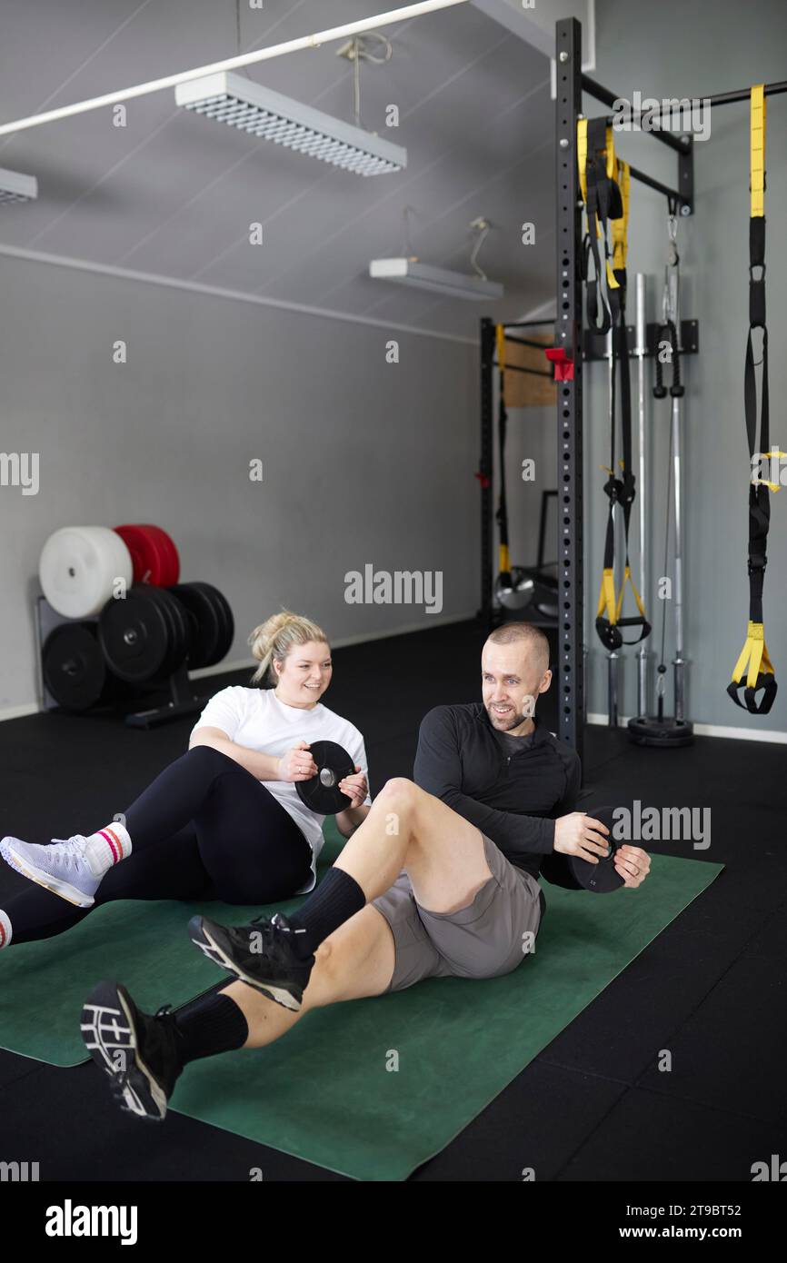 Happy mid adult couple exercising with weights at health club Stock Photo