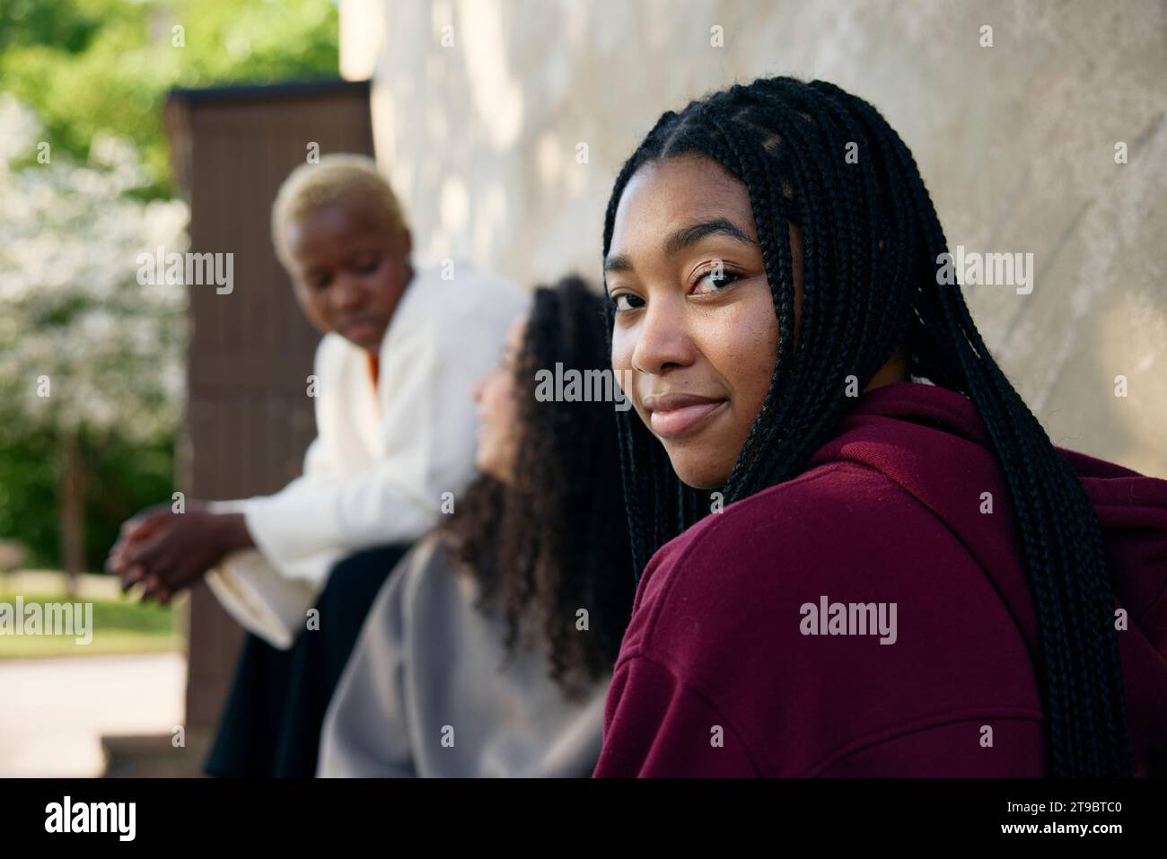 Portrait of woman with braided hair sitting near friends Stock Photo