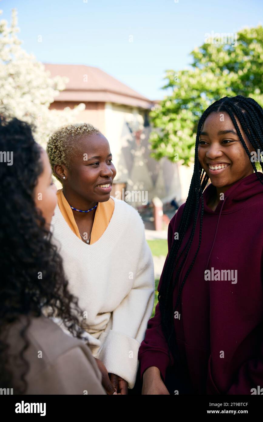Smiling young female friends talking to each other Stock Photo