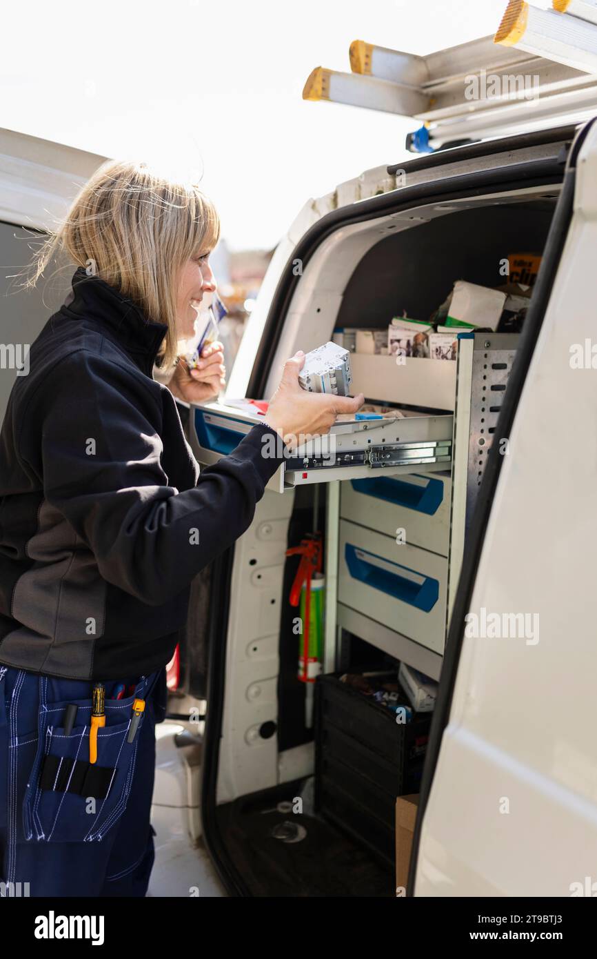 Mature female technician removing tool from drawer inside van Stock Photo