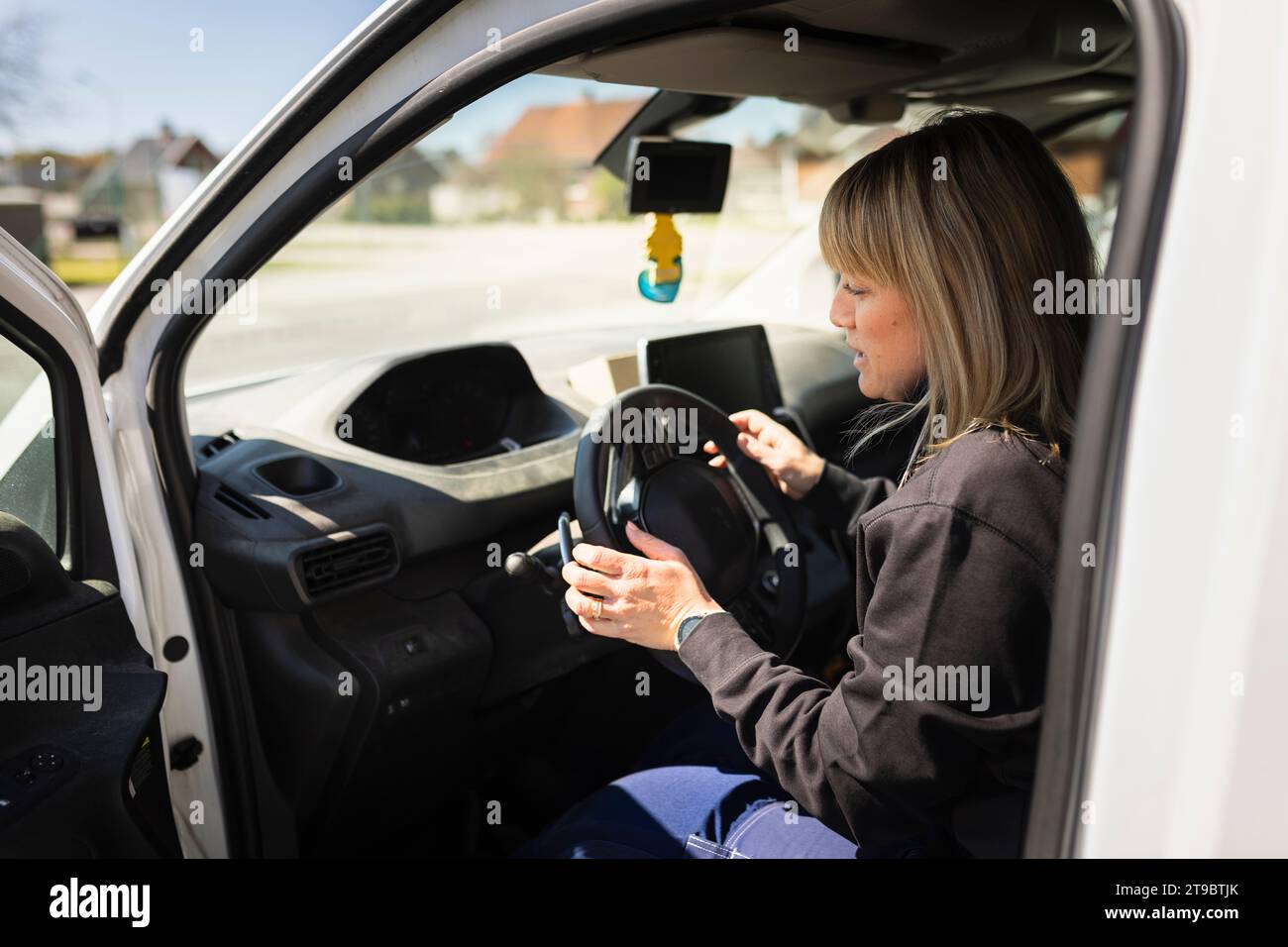 Female electrician sitting on driver's seat in van Stock Photo