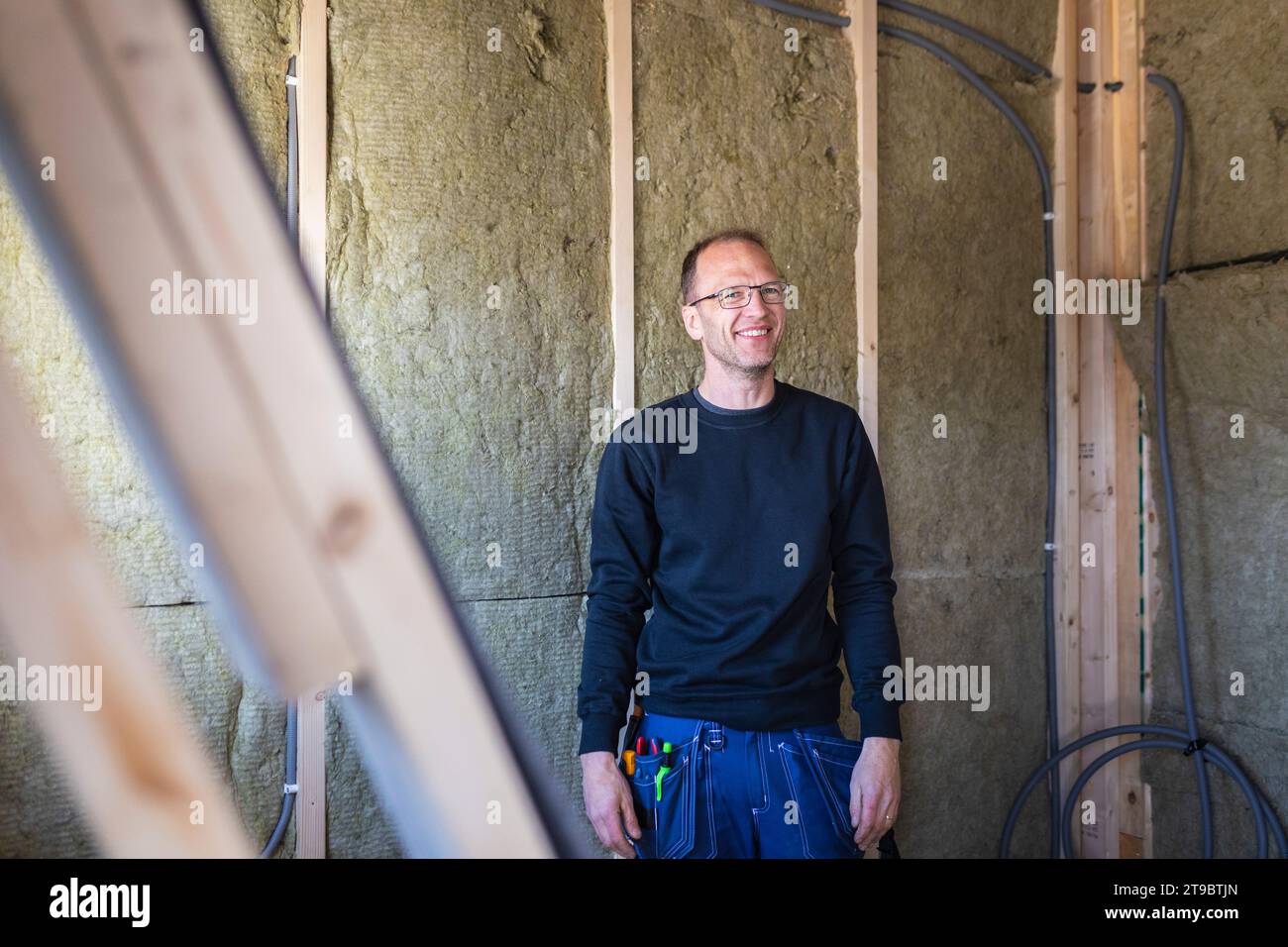 Smiling male electrician standing against wall Stock Photo