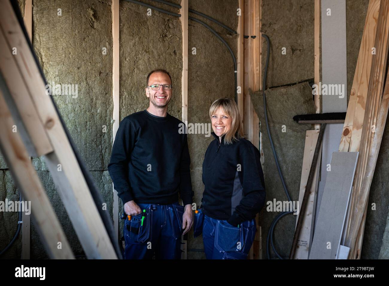Portrait of smiling male and female electrician standing against wall Stock Photo